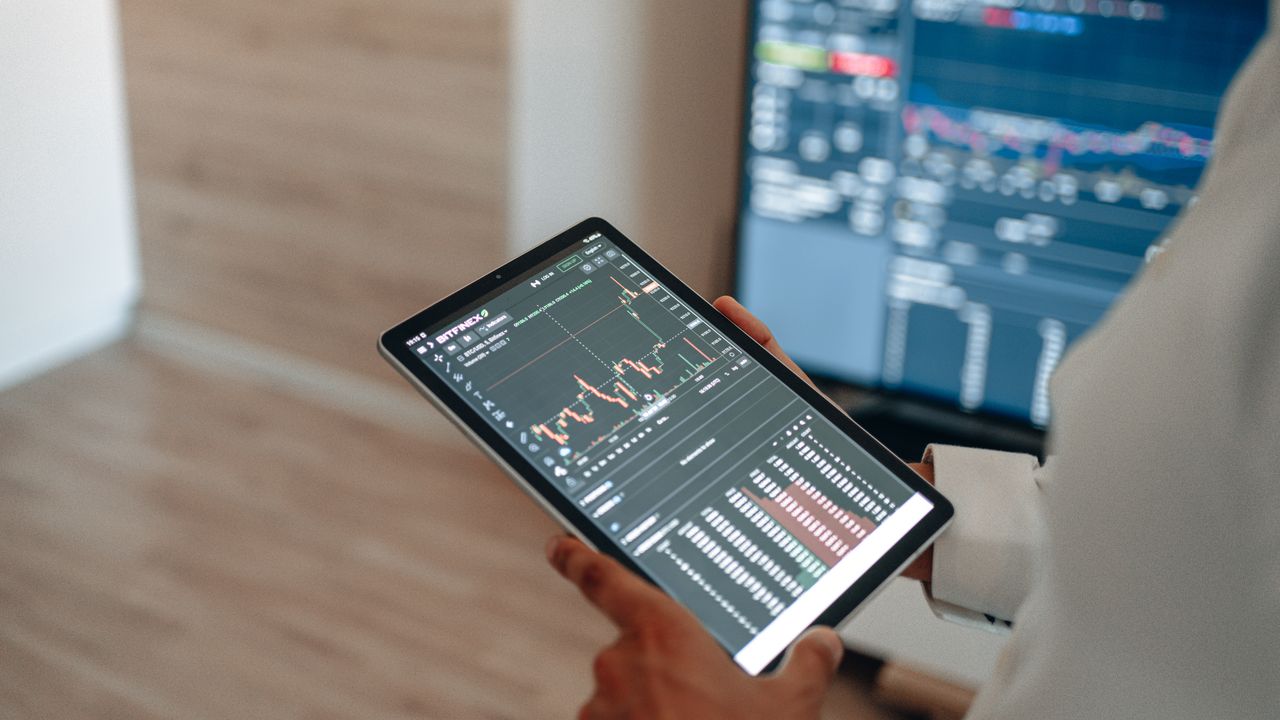 services-02 A person uses a tablet to monitor stock market trends and real-time trading graphs.
