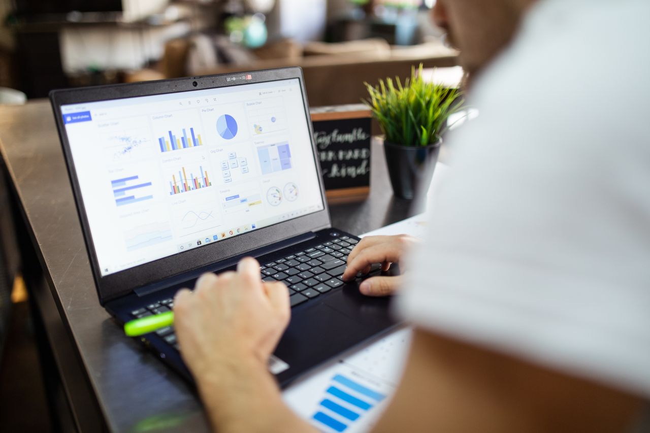 hero-img-02 Focused business analysis with charts and graphs on a laptop in a modern office setting.
